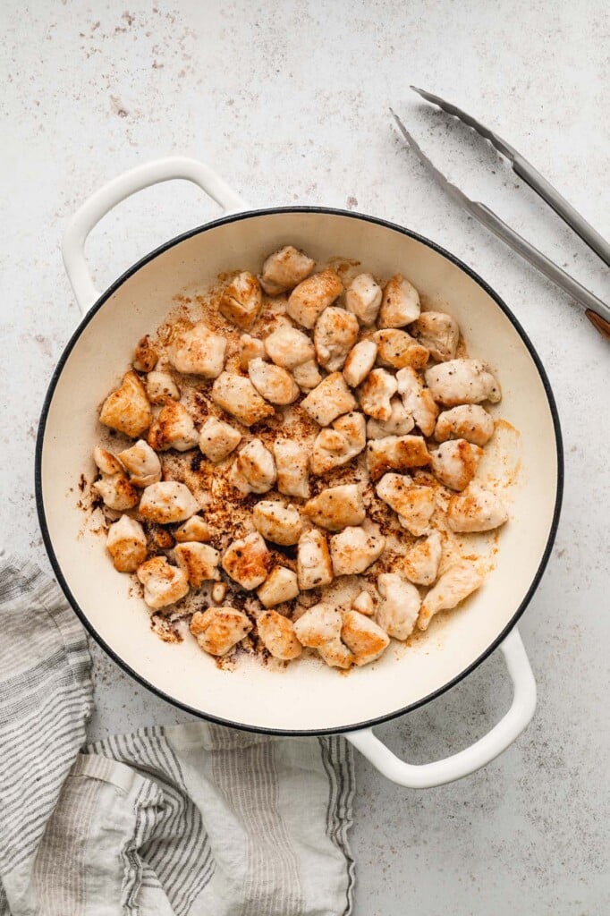 Cooked chicken pieces in a dutch oven that has been browned to make chicken orzo 
