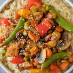 Chicken Stir Fry on a bed of rice in a bowl on a grey background