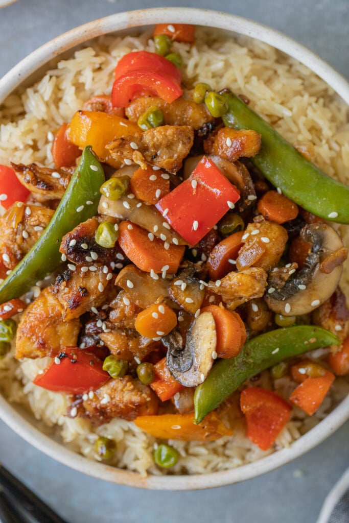 Chicken Stir Fry on a bed of rice in a bowl on a grey background