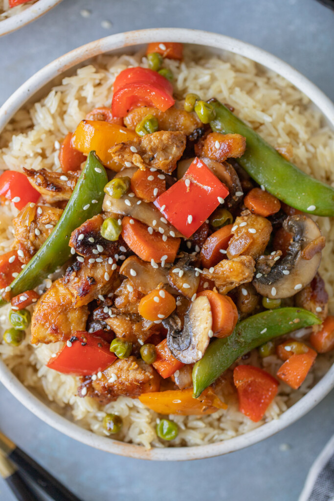 Chicken Stir Fry on a bed of rice in a bowl on a grey background