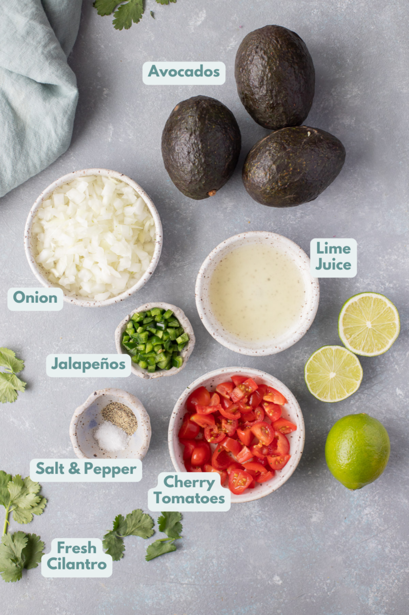 Ingredients for best guacamole in small bowls: ripe avocados, white onions, cherry tomatoes, jalapenos, cilantro, lime juice, salt, pepper
