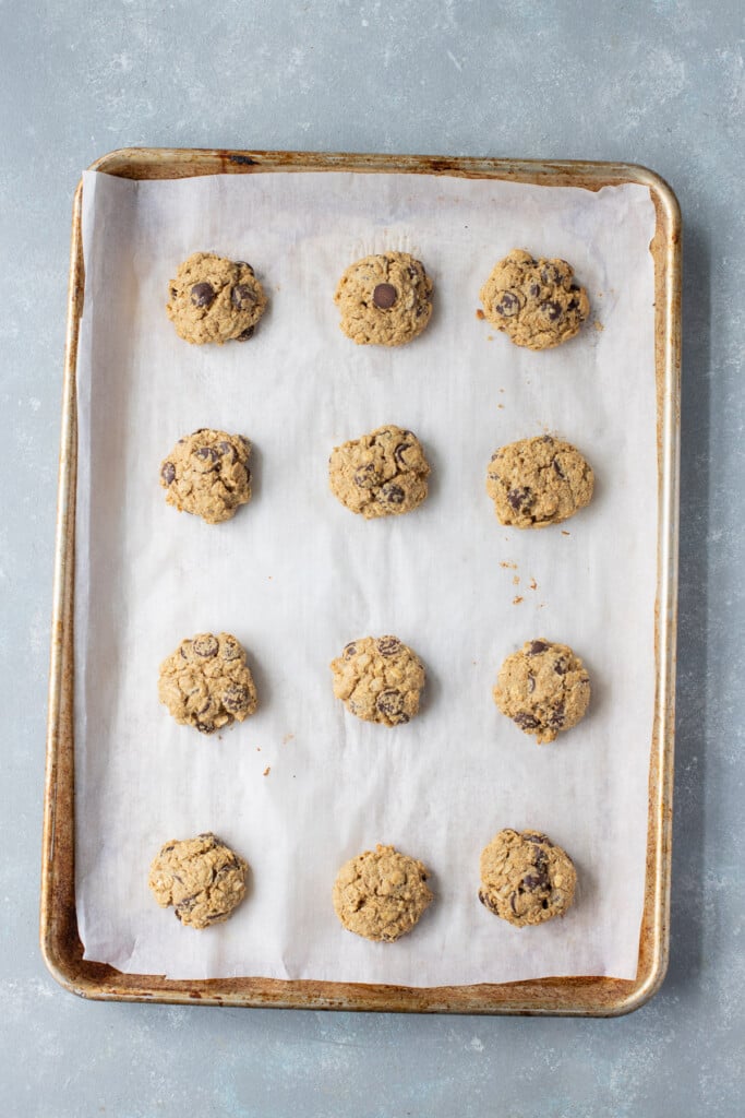 Healthy oatmeal chocolate chip cookies on a parchment lined baking sheet on a grey counter