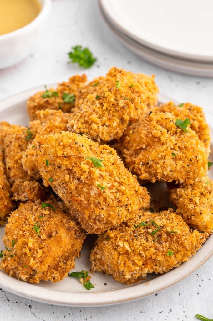 Homemade Healthy Chicken Nuggets piled on a white plate on a white background
