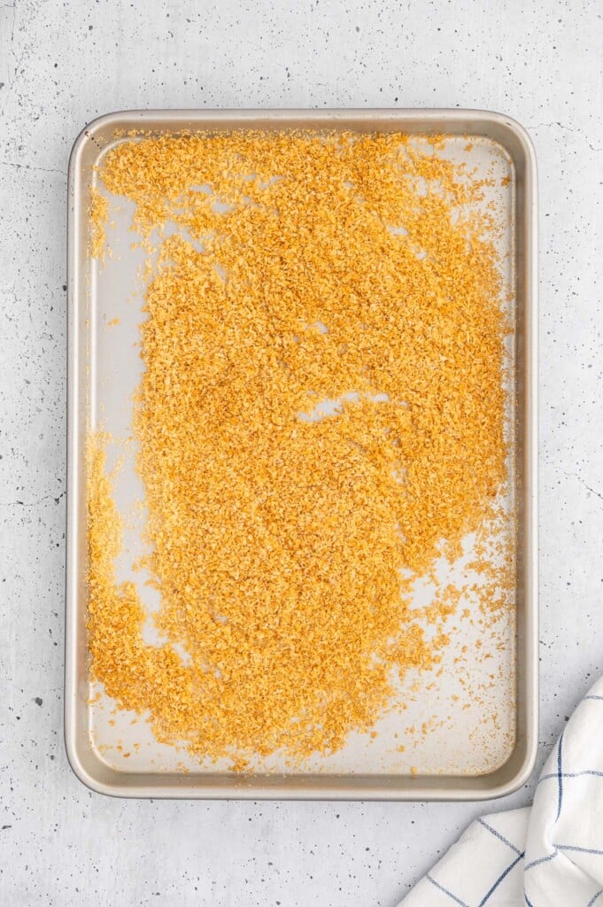 An overhead shot of panko breadcrumbs on a baking sheet on a white counter