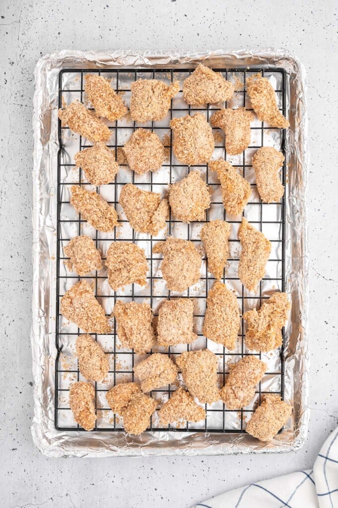 An overhead shot of uncooked homemade chicken nuggets on a wire rack on a baking sheet
