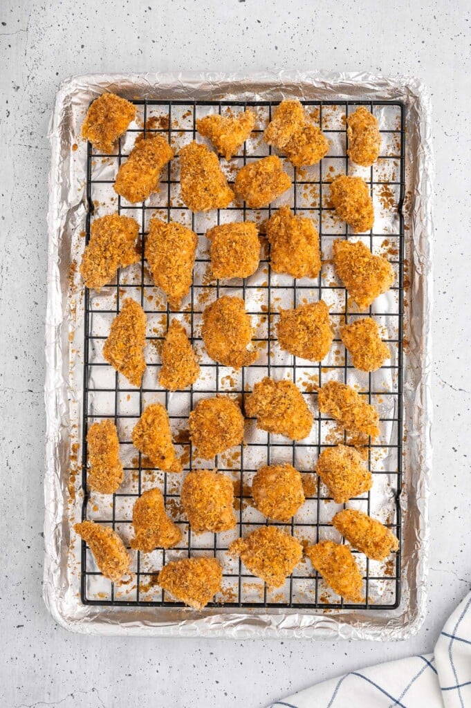 An overhead shot of homemade chicken nuggets on a wire rack on a baking sheet