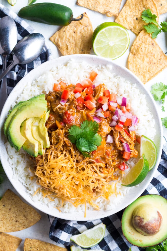 Pumpkin Chicken Chili in a white bowl topped with cheese, tomatoes, limes and avocado for one pot meals