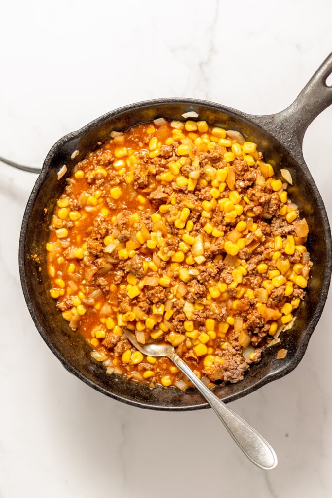 Ground Beef Filling in a cast iron skillet for Taco Zucchini Boats on a marble background.