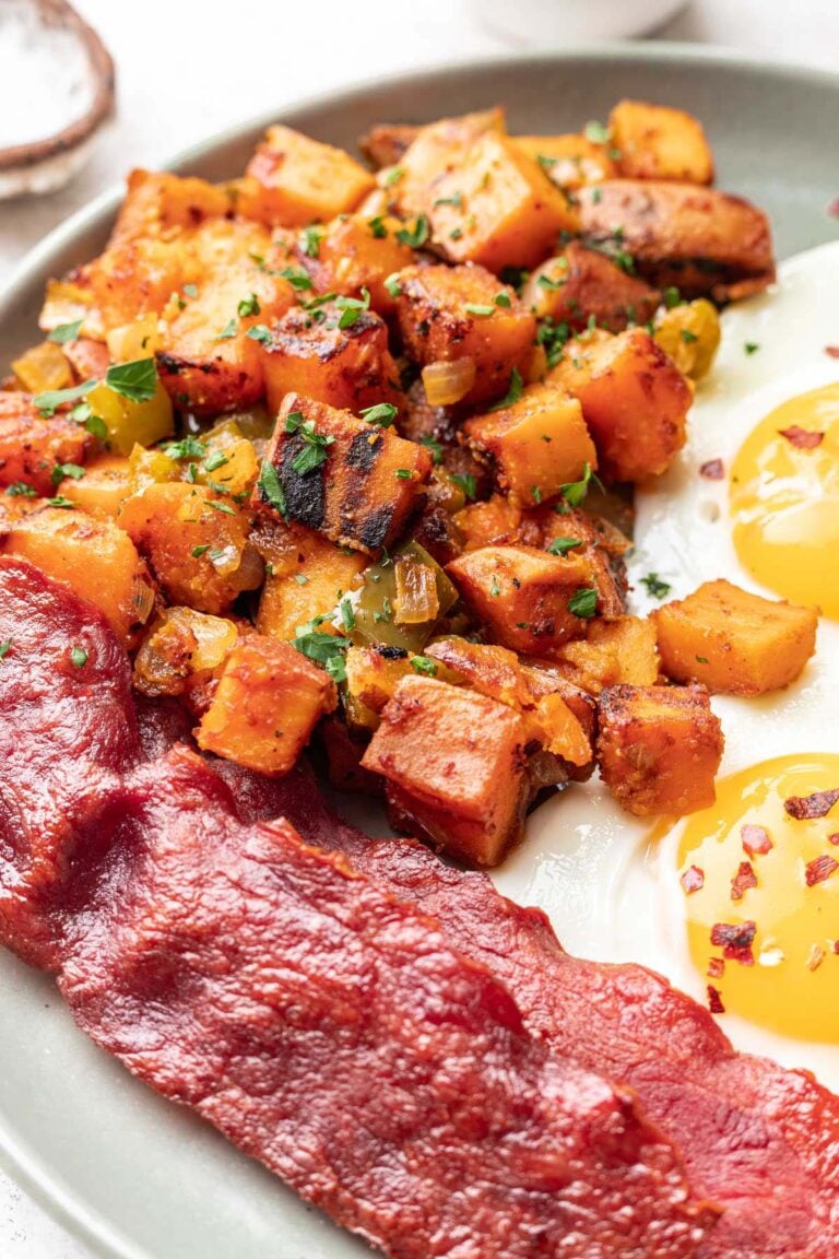 Sweet Potato Home Fries on a grey plate with bacon and sunny side up eggs
