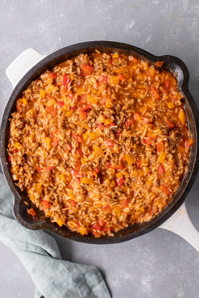 Unstuffed bell peppers in a skillet after the rice has cooked, but before the cheese has been added