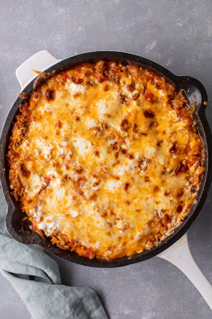 An overhead shot of unstuffed peppers skillet on a grey background with a towel on the side