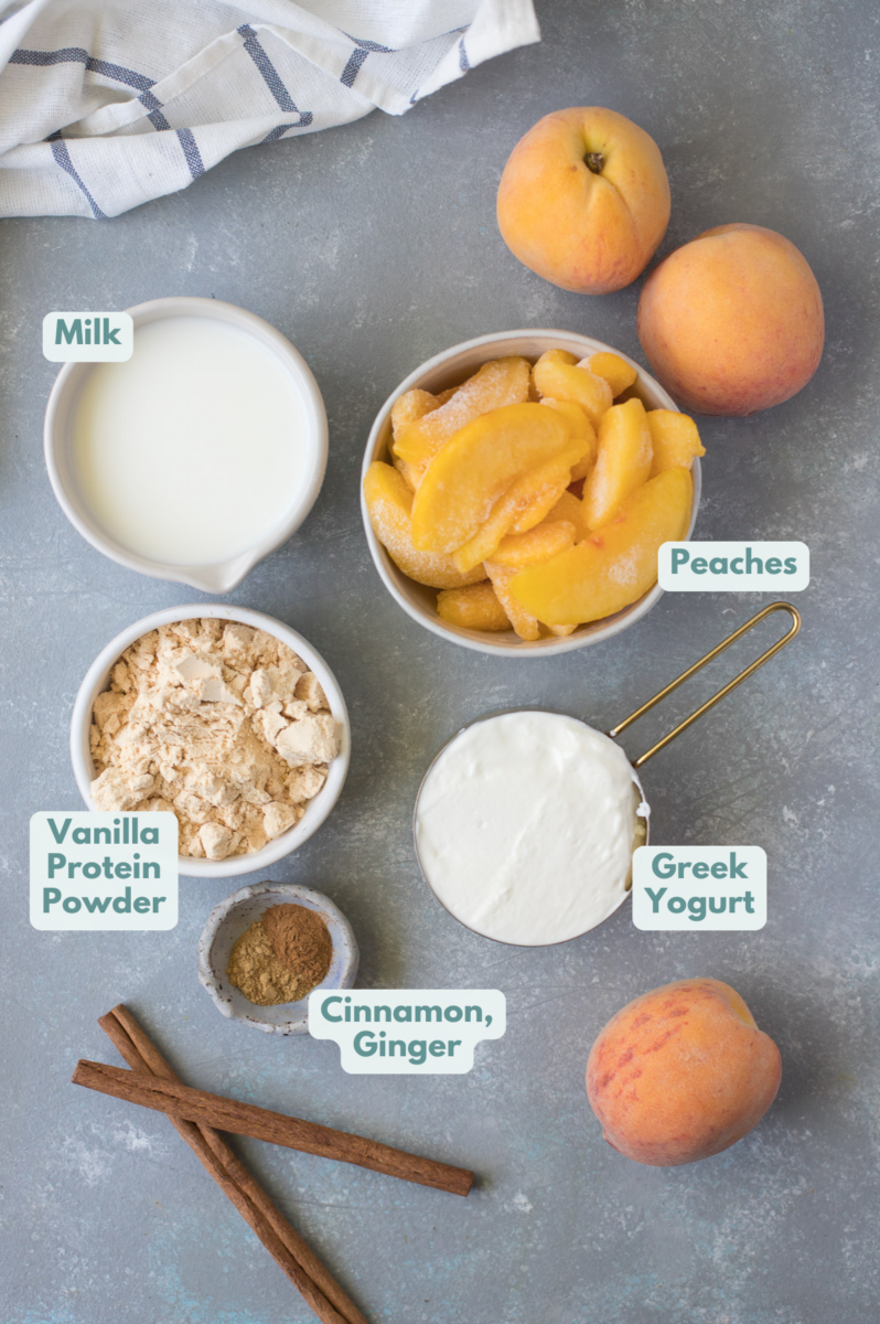 Ingredients for a peach smoothie in small bowls: peaches, greek yogurt, milk, vanilla protein powder, cinnamon, ginger