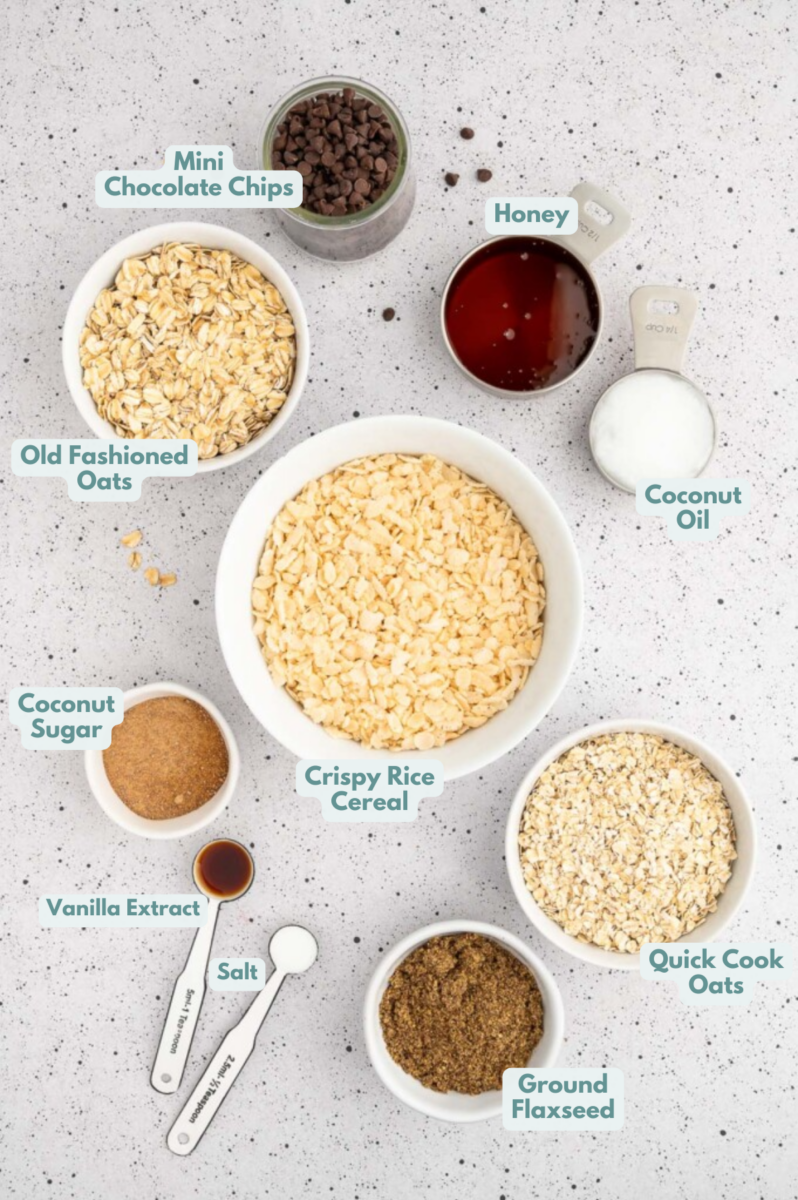 Ingredients for healthy granola bars in small bowls: old fashioned oats, quick cook oats, honey, coconut oil, coconut sugar, vanilla extract, crispy rice cereal, ground flaxseed, sea salt, mini chocolate chips