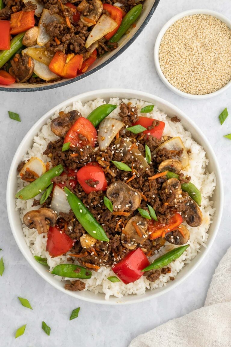 Ground Beef Stir Fry on a bed of rice on a plate with a dutch oven of the stirfry on the side