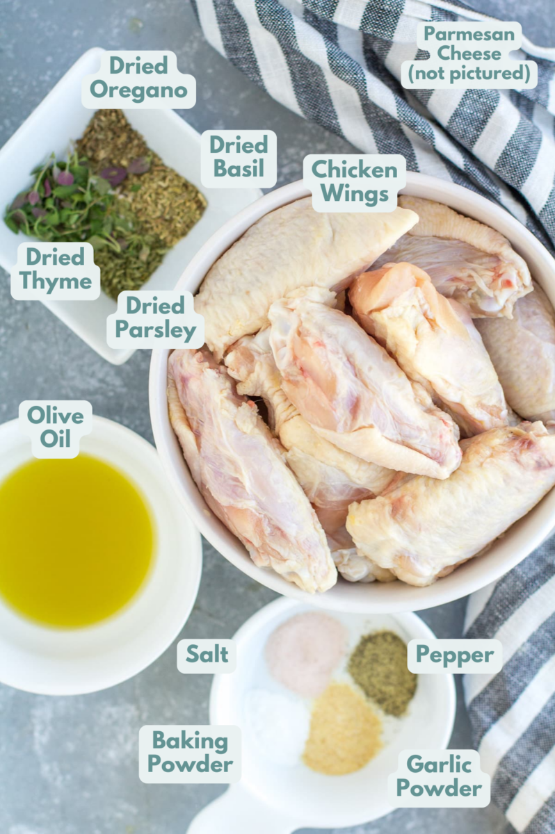 Ingredients for garlic parmesan chicken wings in small white bowls - wings, olive oil, spices and cheese