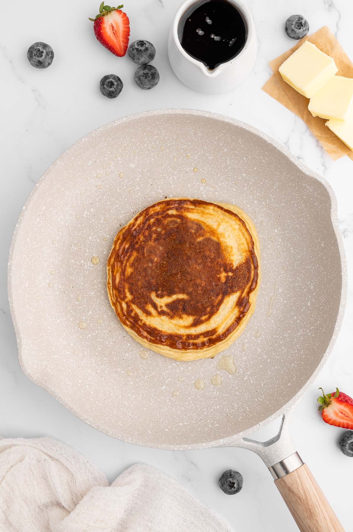 Overhead of a cooked pancake in a white skillet.