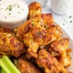 Baked Chicken Wings on a plate with celery and a container of ranch dip on the side.