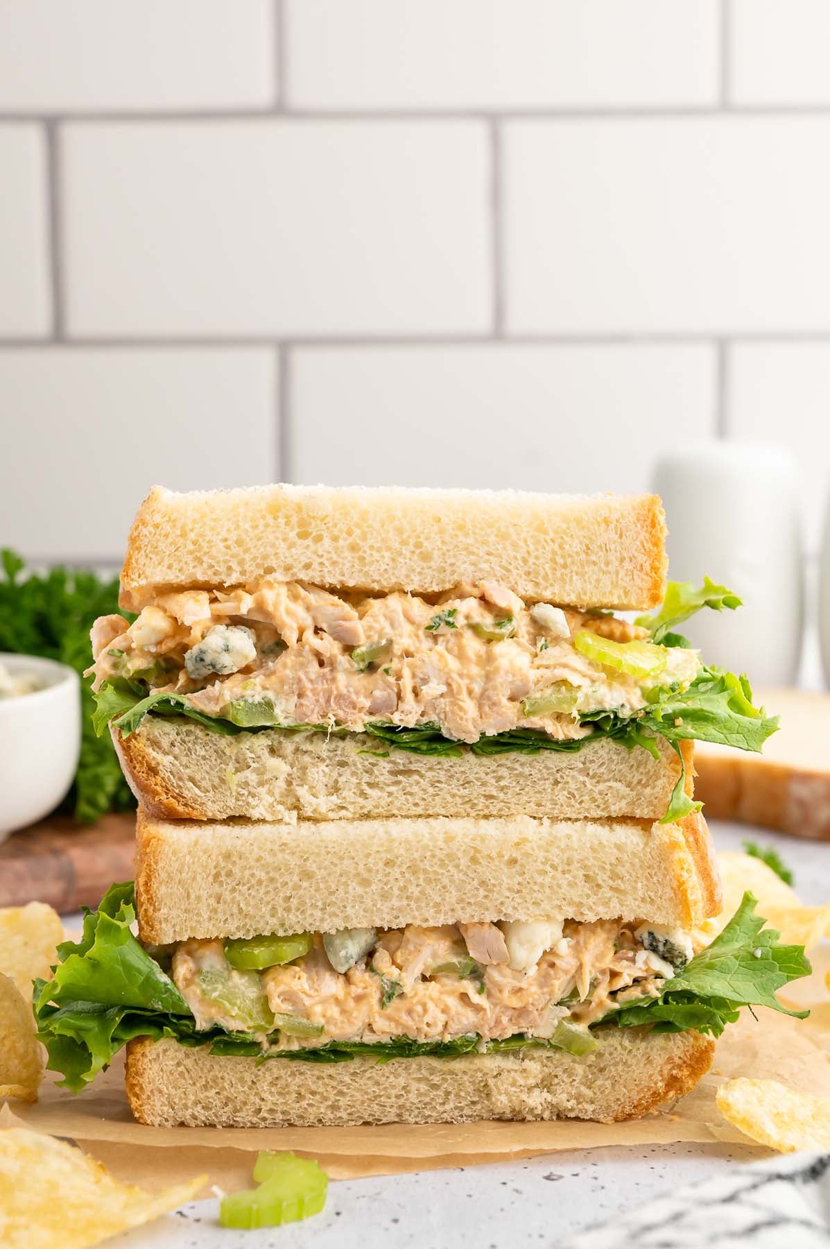 Buffalo chicken salad served on bread with crisp lettuce. The two halves of the sandwich are stacked.