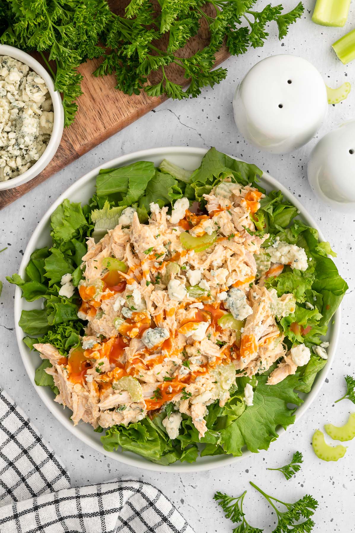 Buffalo chicken salad with blue cheese crumbles on a bed of lettuce in a white bowl.