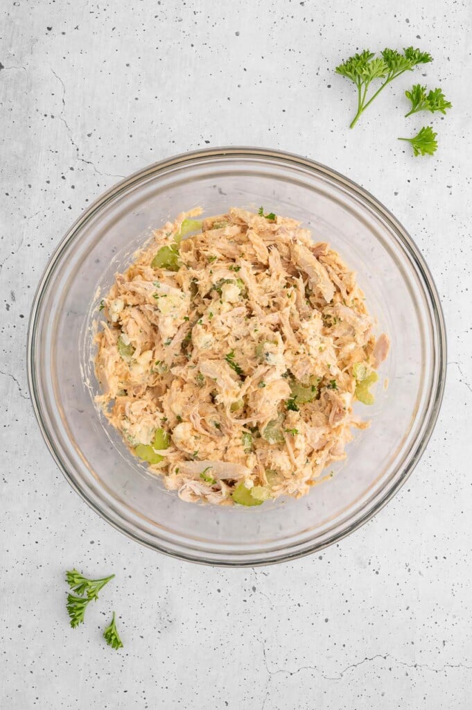 Buffalo chicken salad in a clear mixing bowl, viewed from overhead.