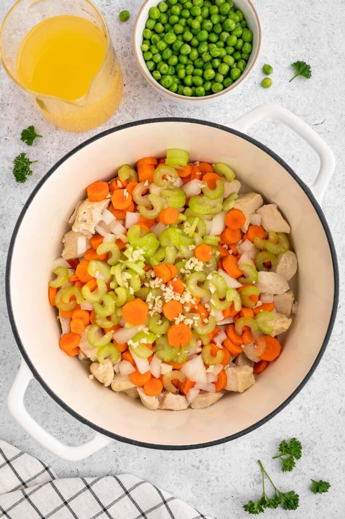 Chicken, onion, garlic, carrots, and celery in a dutch oven before cooking to make gluten free chicken pot pie.