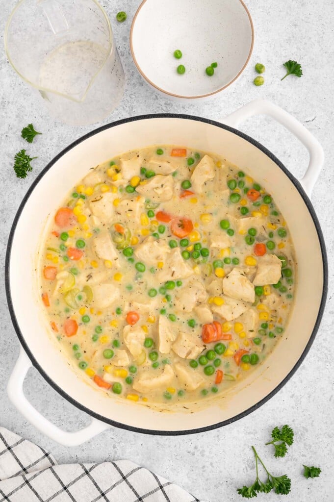 Fully cooked crustless chicken pot pie in a dutch oven on a white background.