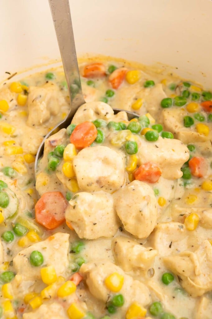 A ladle dipping in a dutch oven of crustless chicken pot pie.