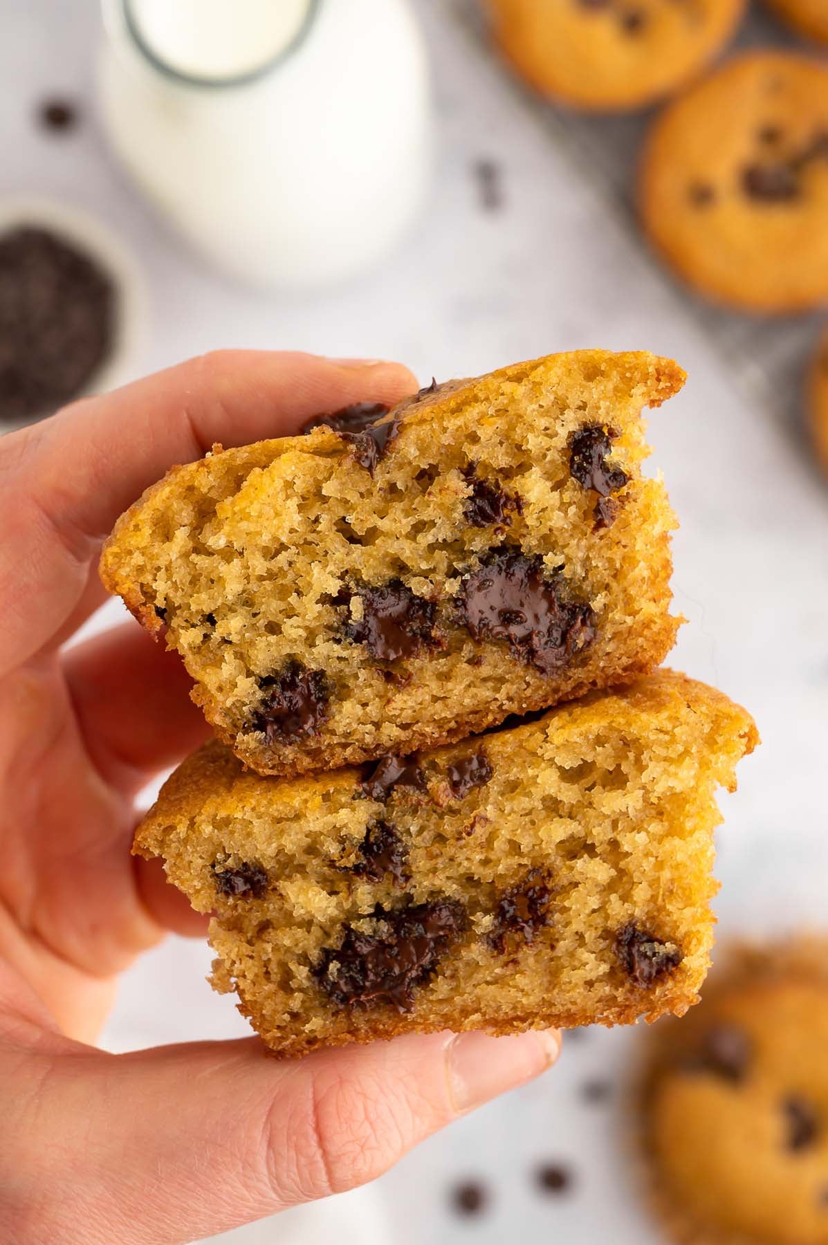 Two halves of oat flour muffins stacked on each other held up by a hand.