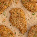 Baked chicken cutlets on a piece of parchment paper.