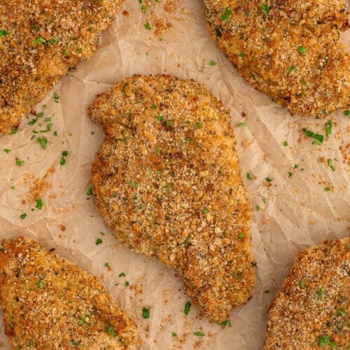 Baked chicken cutlets on a piece of parchment paper.