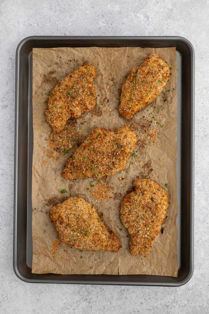 Crispy Baked Chicken Cutlets on a parchment lined baking sheet.