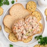 Healthy Tuna Salad on an open faced sandwich surrounded by crackers on a plate.