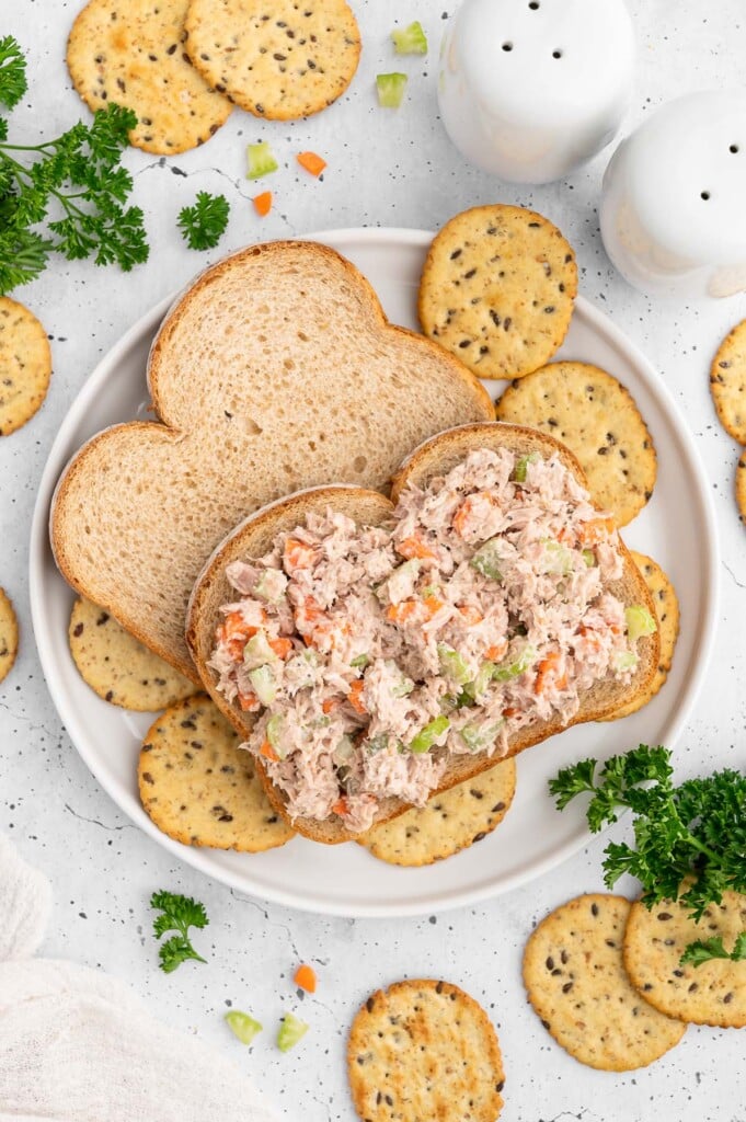Healthy Tuna Salad on an open faced sandwich surrounded by crackers on a plate.