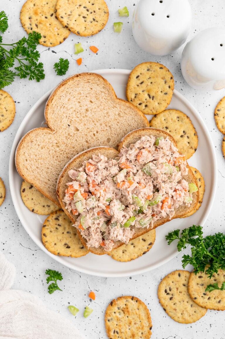 Healthy Tuna Salad on an open faced sandwich surrounded by crackers on a plate.