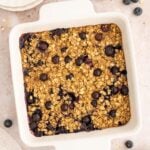 A white baking dish of Healthy Blueberry Baked Oatmeal with blueberries on the side.