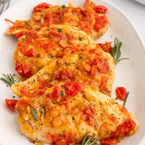 Chicken Scarpariello on a white platter on a white counter.