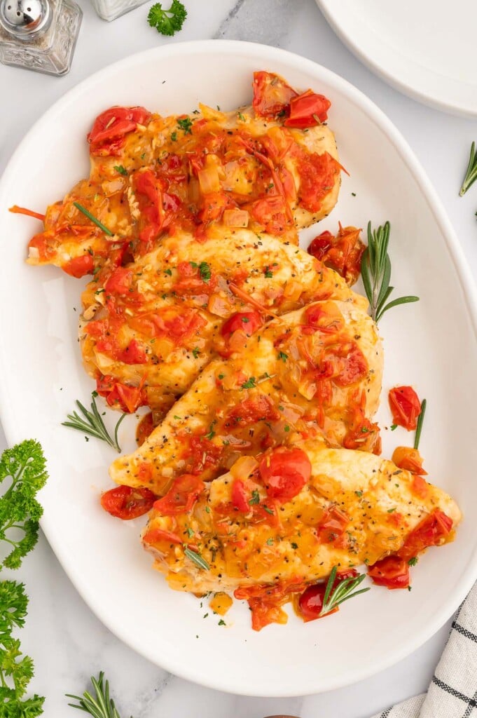 Chicken Scarpariello on a white platter on a white counter.