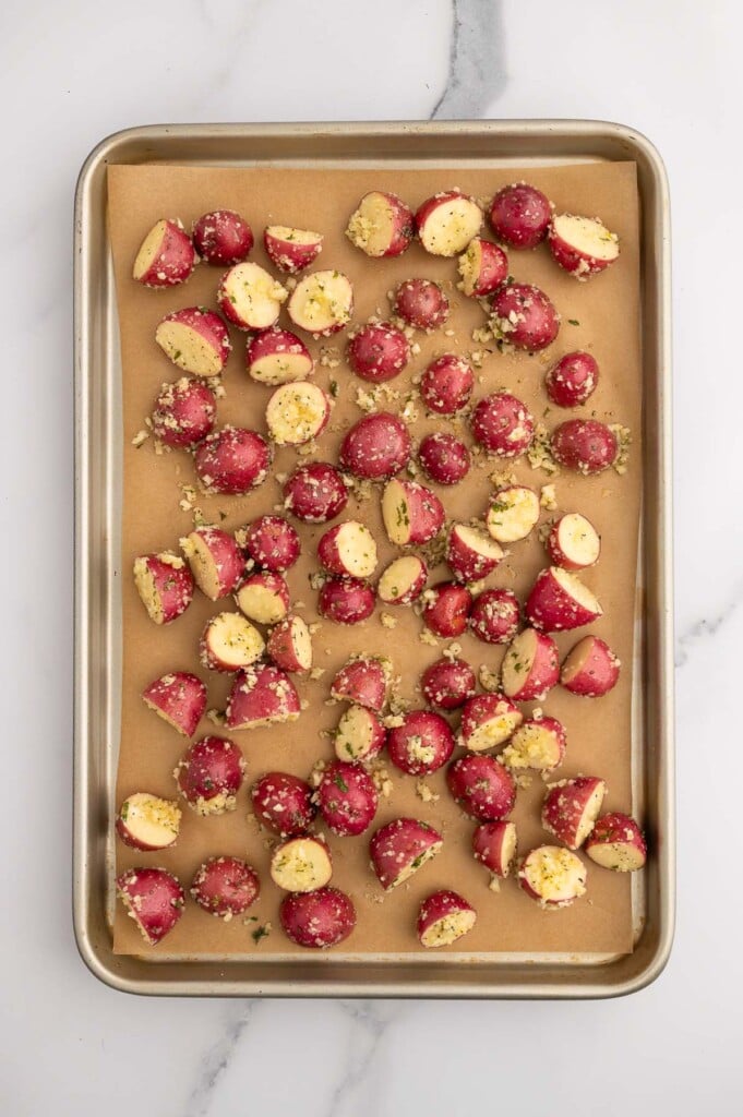 Red garlic potatoes on a parchment lined baking sheet before roasting.