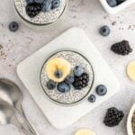 An overhead shot of two jars of chia seed pudding topped with berries and banana slices.