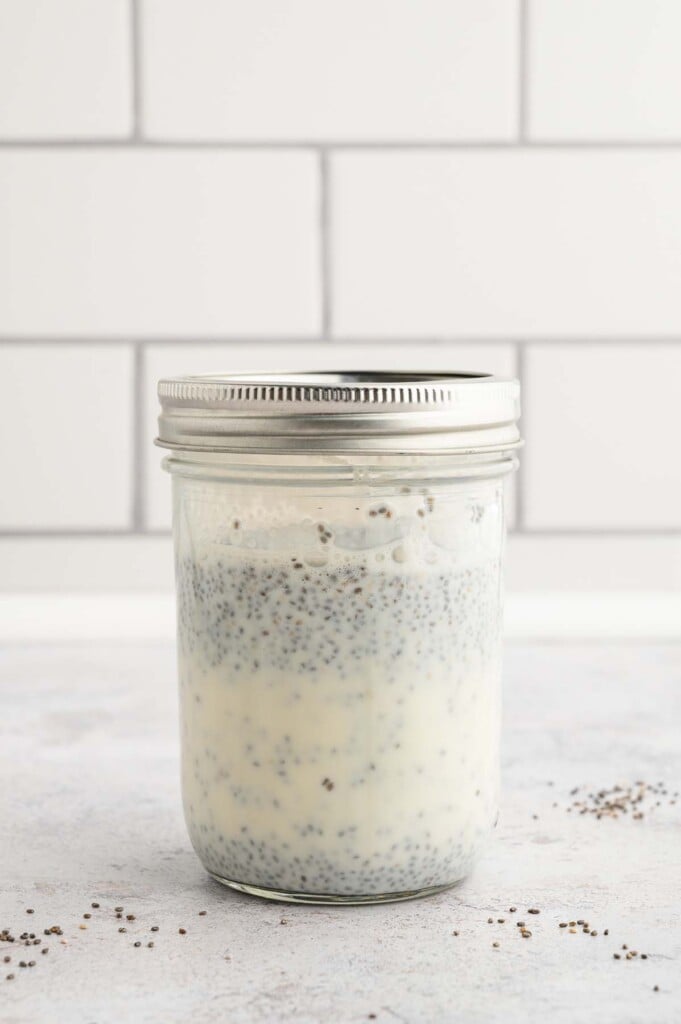 A mason jar with chia seed pudding that hasn't fully set, so the seeds and milk are still separated.