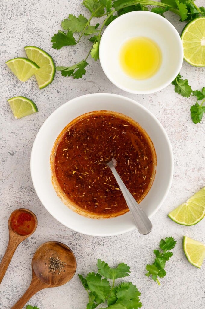 Chili lime chicken marinade in a white bowl with a spoon in it, viewed from overhead.