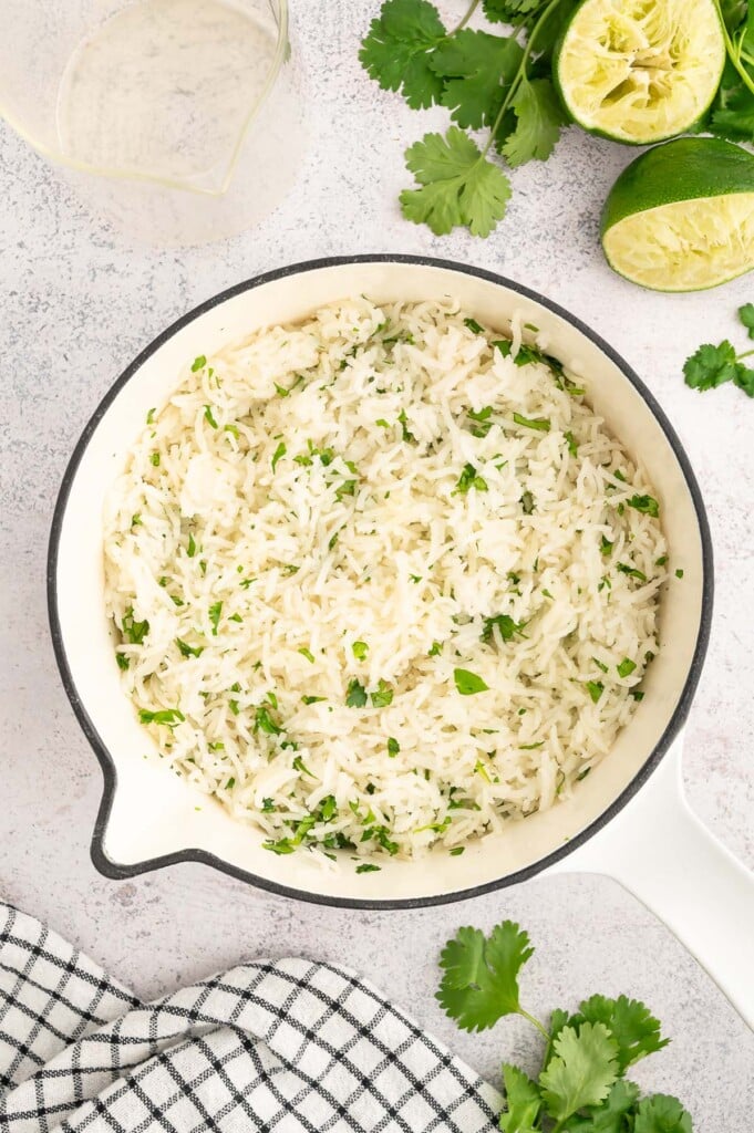 Cilantro Lime Rice in a pot with limes and cilantro on the side. 