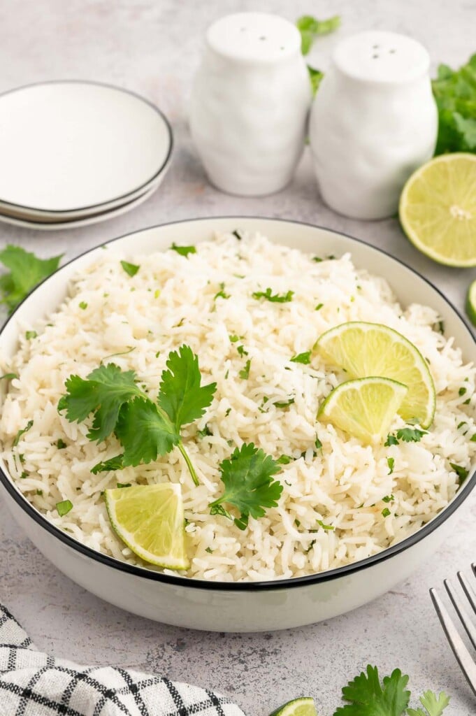Cilantro Lime Rice in a bowl garnished with cilantro and limes.