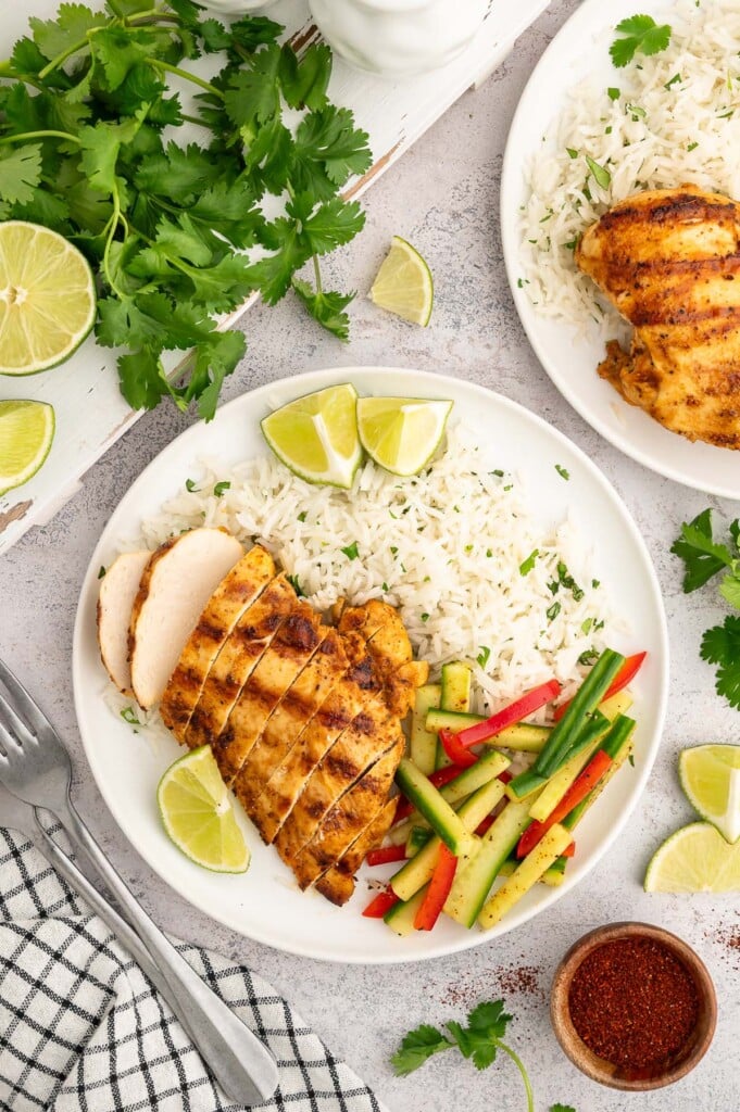 An overhead shot of Cilantro Lime Rice, a sliced Chili Lime Chicken Breast, and pickled veggies on a white plate.
