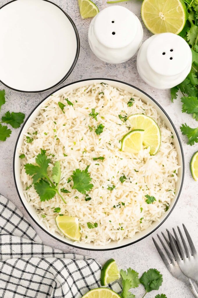 An overhead shot of cilantro lime rice in a pot garnished with chopped cilantro and lime slices.
