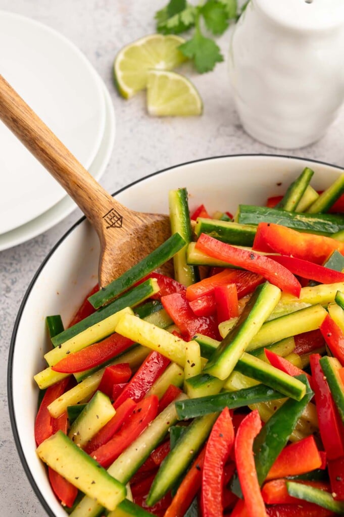 A wooden spoon in a bowl of marinated vegetable salad. 