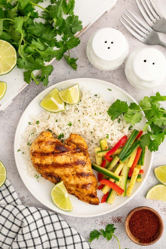 An overhead shot of marinated vegetable salad on a white plate with Cilantro Lime Rice, and Chili Lime Chicken Breast.