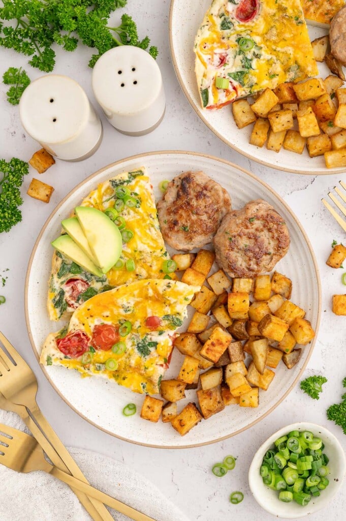 Turkey breakfast sausage patties on a white plate with two slices of egg white frittata and breakfast potatoes on the side.