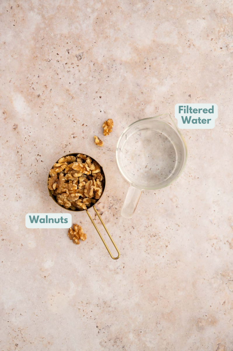 Ingredients for walnut milk in a cup and measuring cup: walnuts and water.