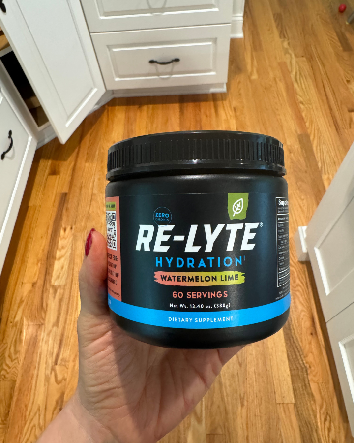 A hand holding a container of relyte watermelon lime electrolytes